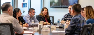 a diverse group of people sitting around a conference table discussing procurement options.